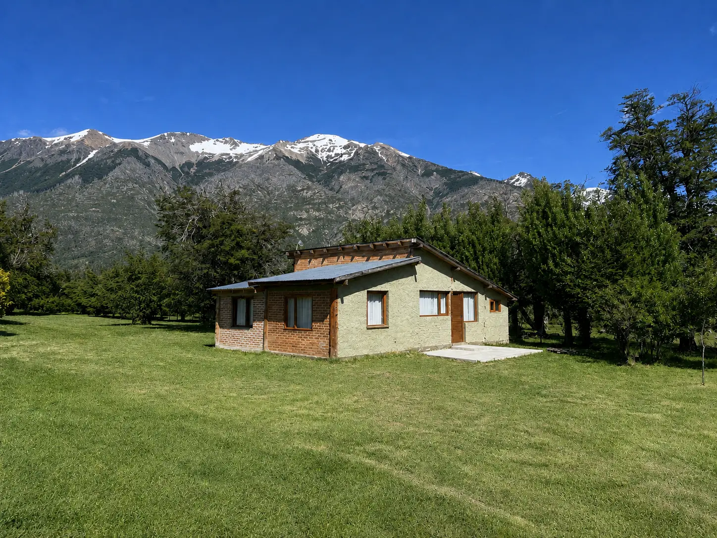 Exterior de Nido Patagónico con montañas nevadas al fondo