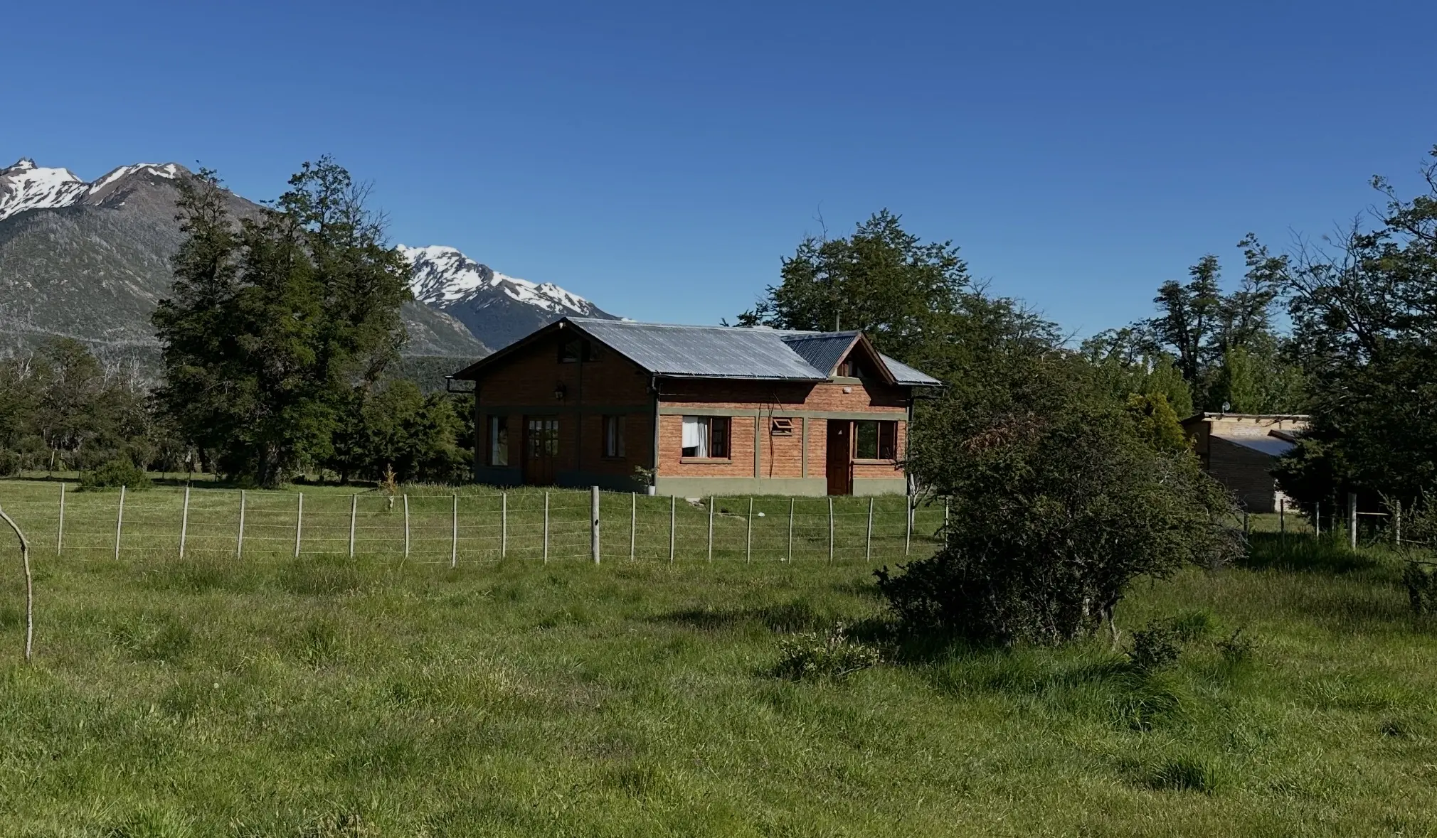 Refugio Cordillerano rodeado de pasto y montañas nevadas
